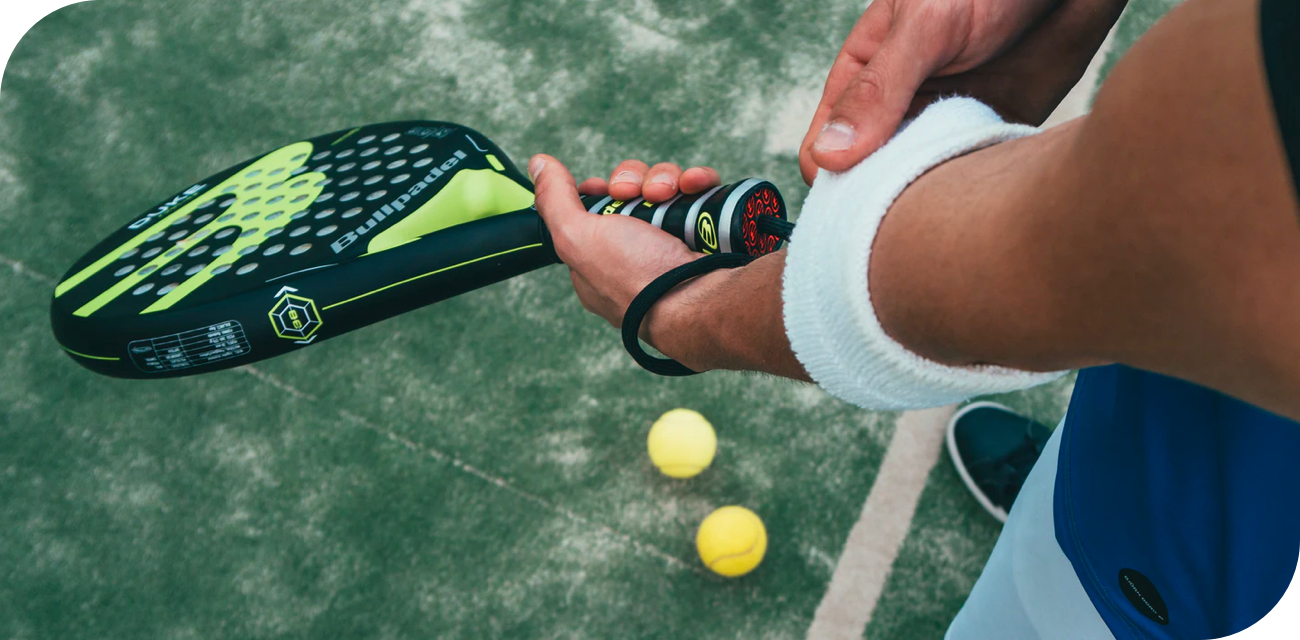 Man adjusting his wristband holding a Bullpadel padel racket on court